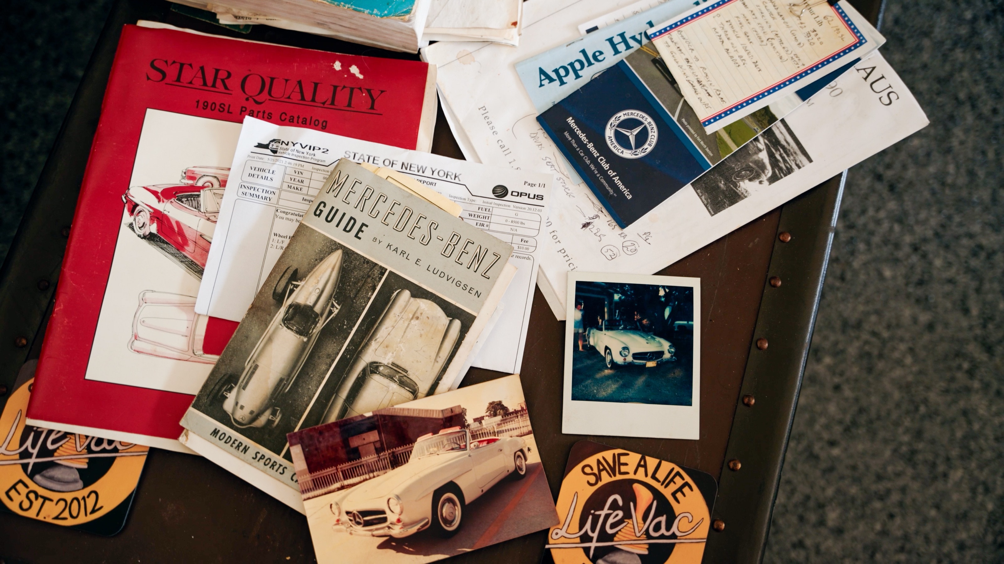 Alte Zeitschriften, Fotos und Aufkleber rund um den 190 SL auf einem Tisch ausgebreitet