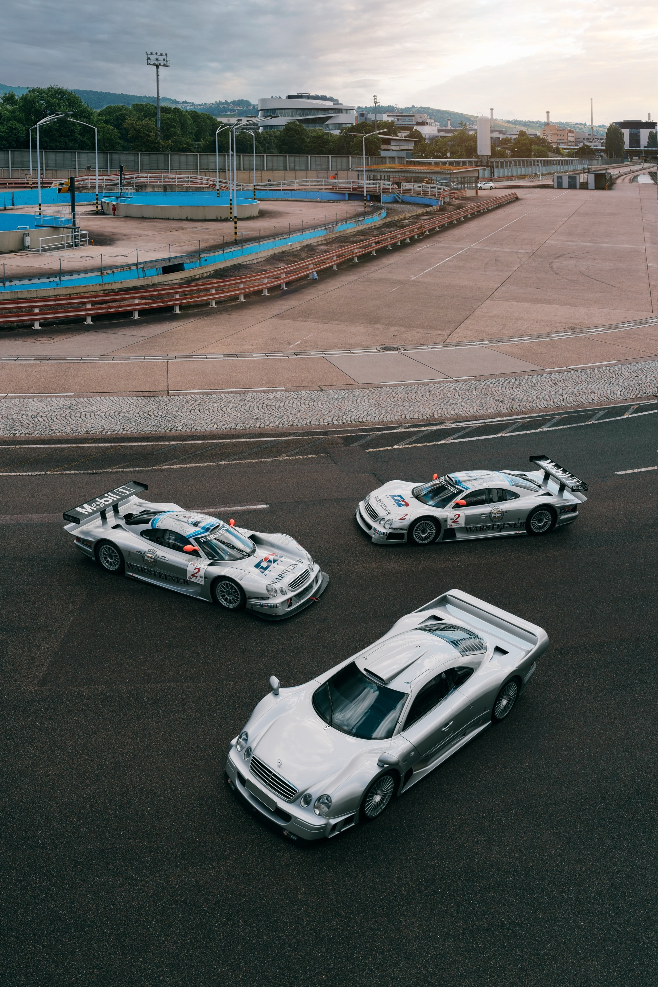 Drei CLK GTR aus erhöhter Perspektive auf dem Asphalt, dahinter das Gelände der Einfahrbahn