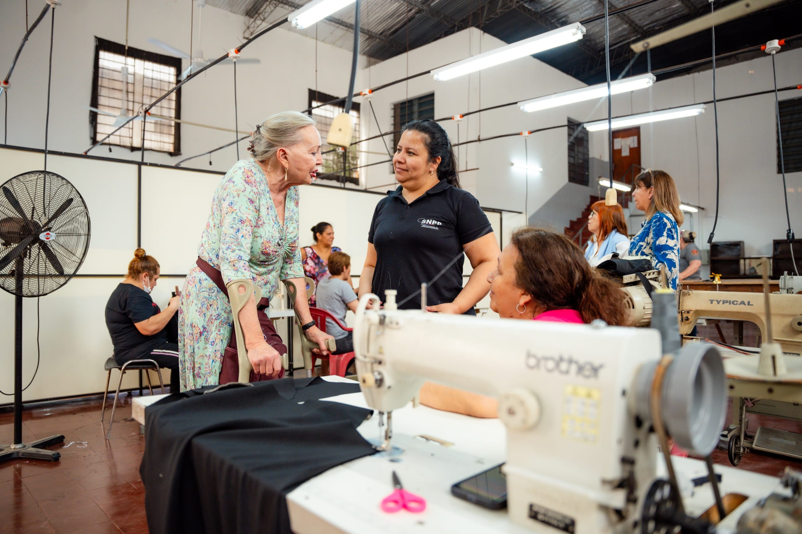 Gespräch zwischen zwei Frauen in der Nähwerkstatt der Stiftung, im Vordergrund eine Industrienähmaschine