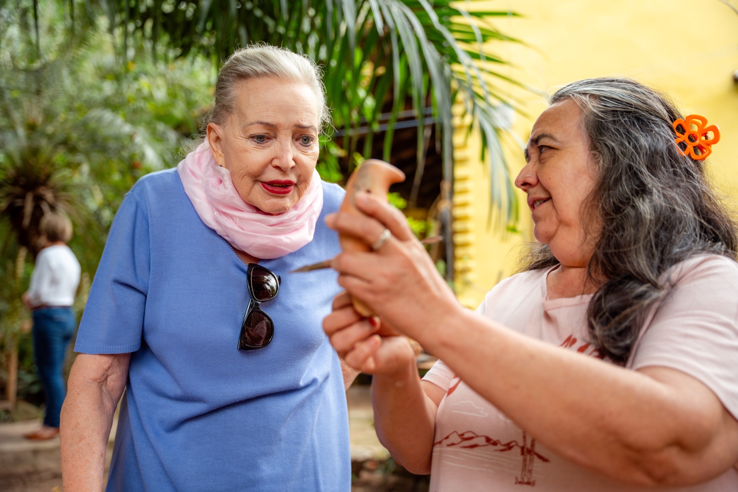 Diane Herzogin von Württemberg im Garten der Stiftung, eine Frau zeigt ihr ein kleines, handgefertigtes Tonstück