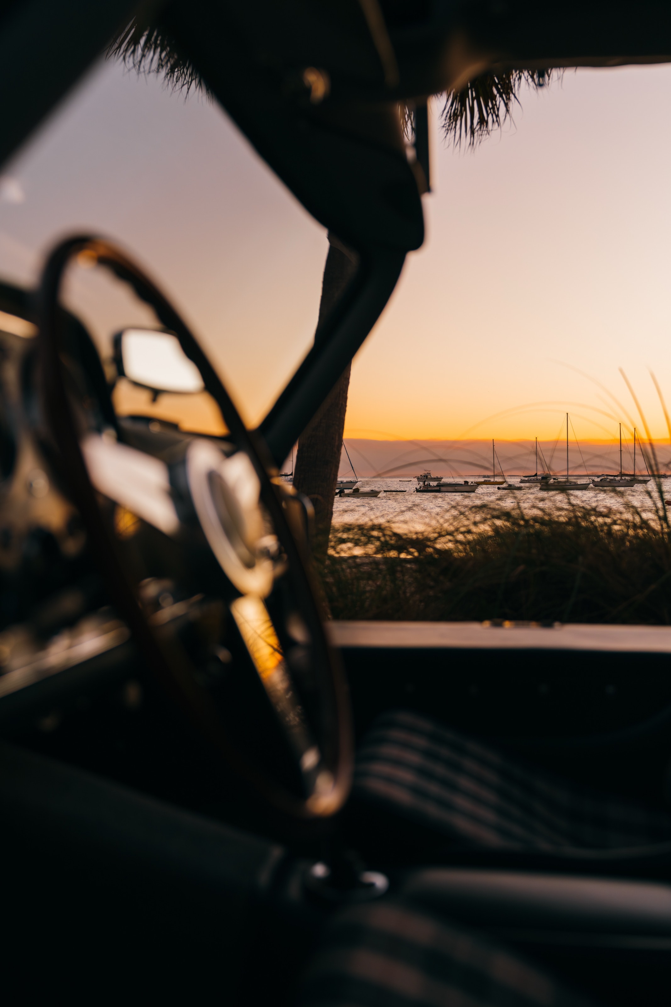 Blick durch das Cockpit des 300 SL am Lenkrad vorbei auf das Meer im Sonnenuntergang