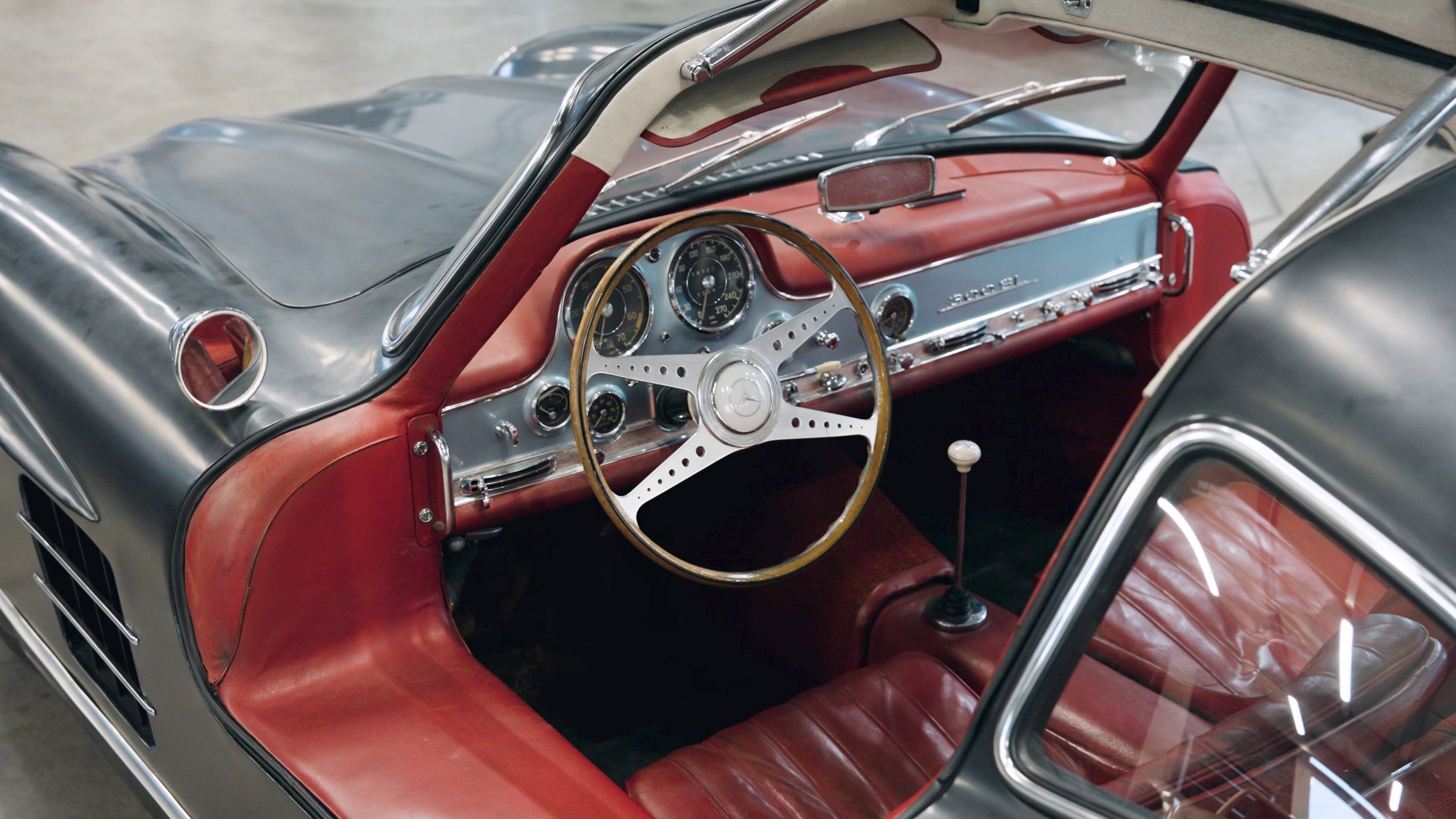 Blick in das rote Interieur eines anthrazitfarbenen 300 SL Gullwing mit geöffneter Flügeltür in der Werkstatt von Bechtel Classic Motors