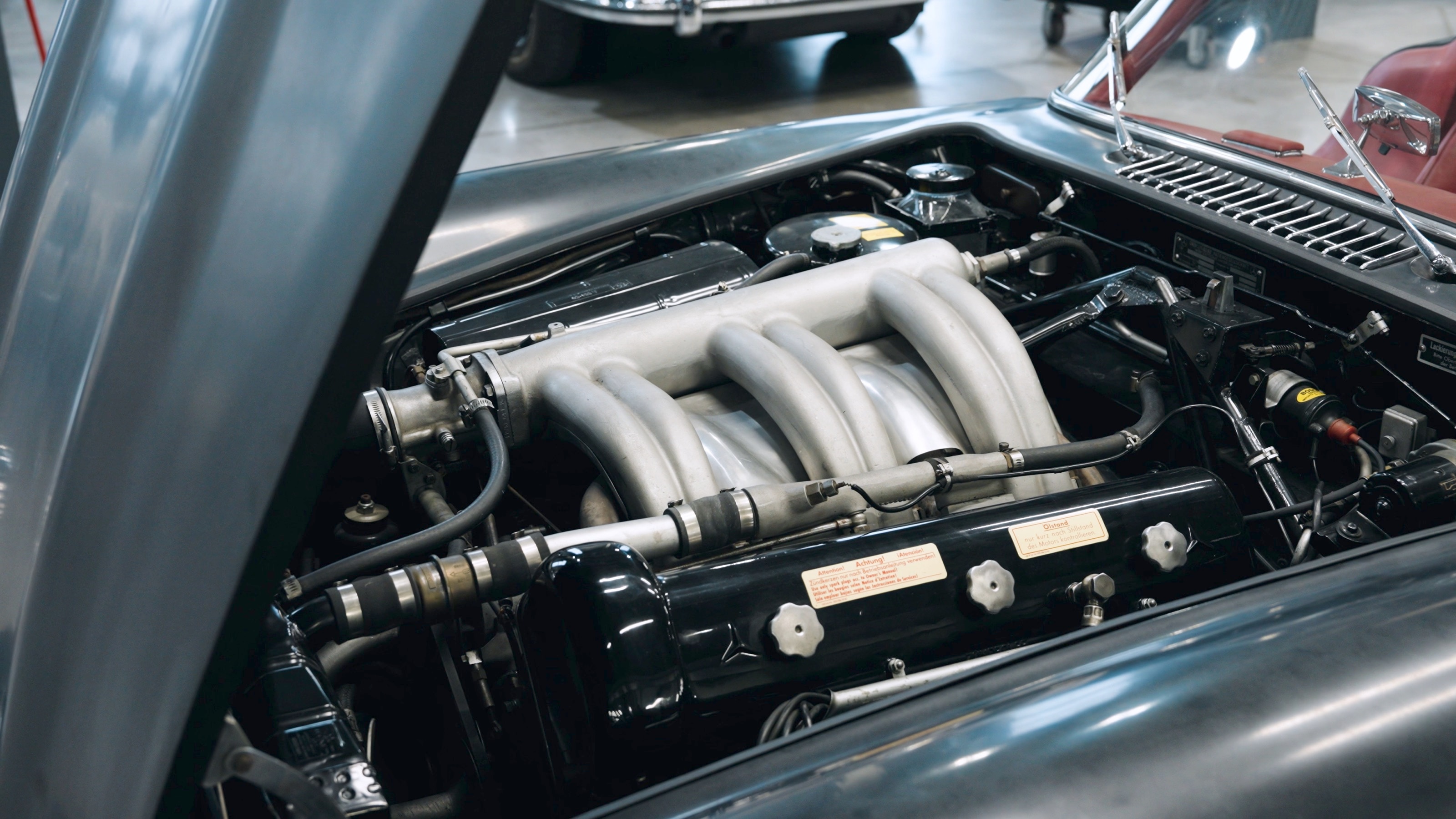 Geöffnete Motorhaube mit dem Reihensechszylinder und seinem Ansaugkrümmer in der Werkstatt