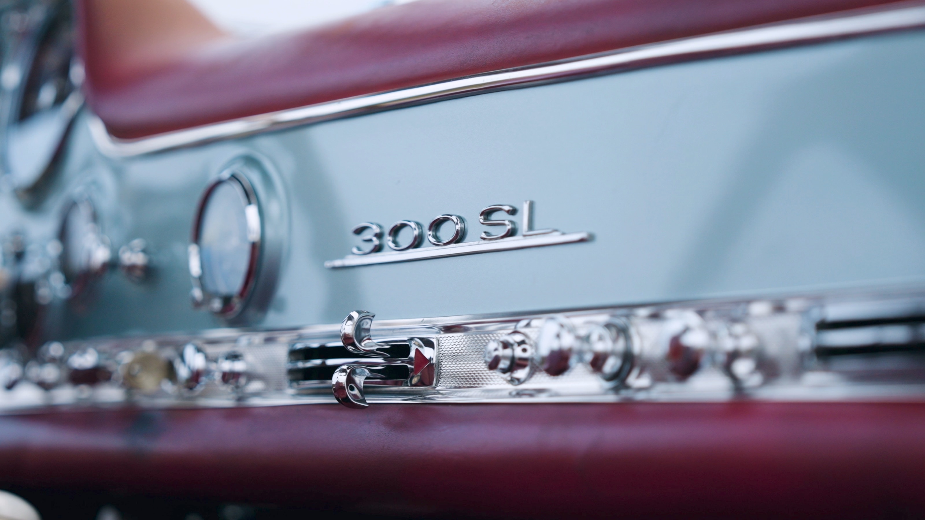 Nahaufnahme des Schriftzugs „300 SL“ auf dem hellblauen Armaturenbrett zwischen roter Lederpolsterung und Chromschaltern