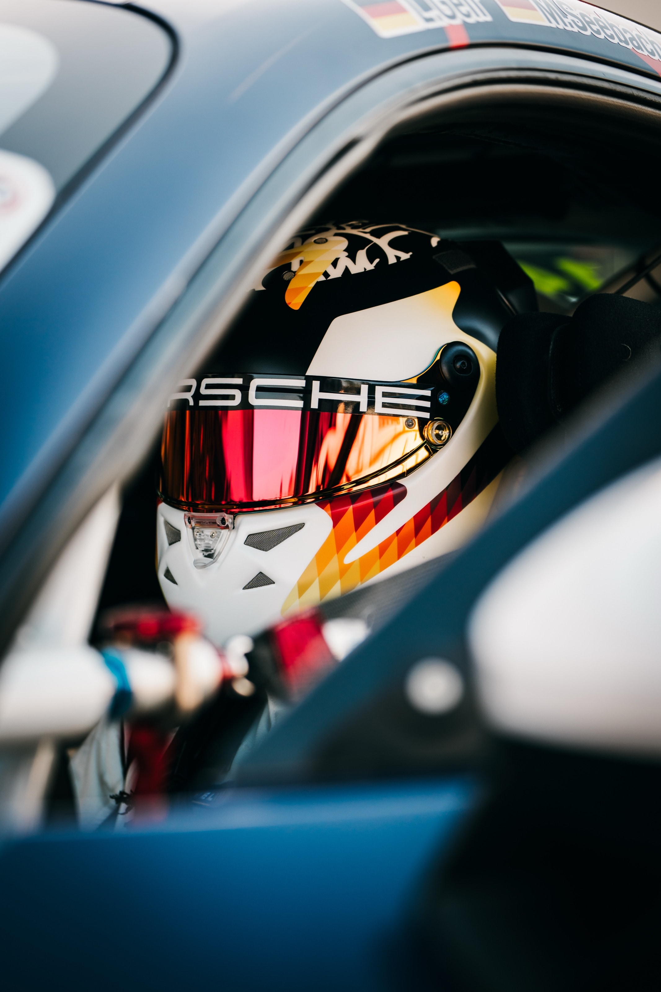 Fahrer mit Helm im Cockpit des 911 GT3 Cup, durch das Seitenfenster fotografiert