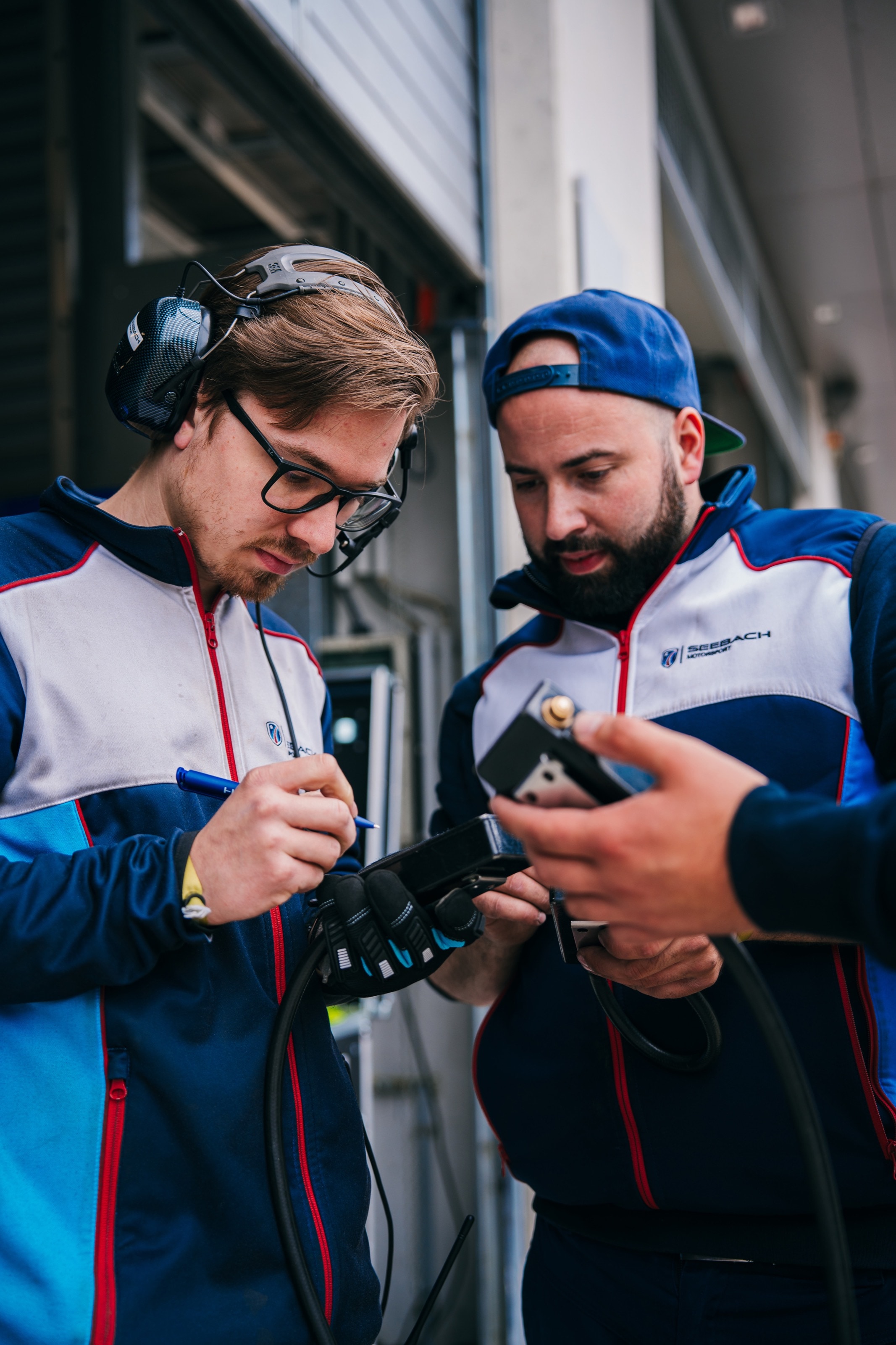 Zwei Ingenieure von Seebach Motorsport prüfen Daten auf einem Handgerät