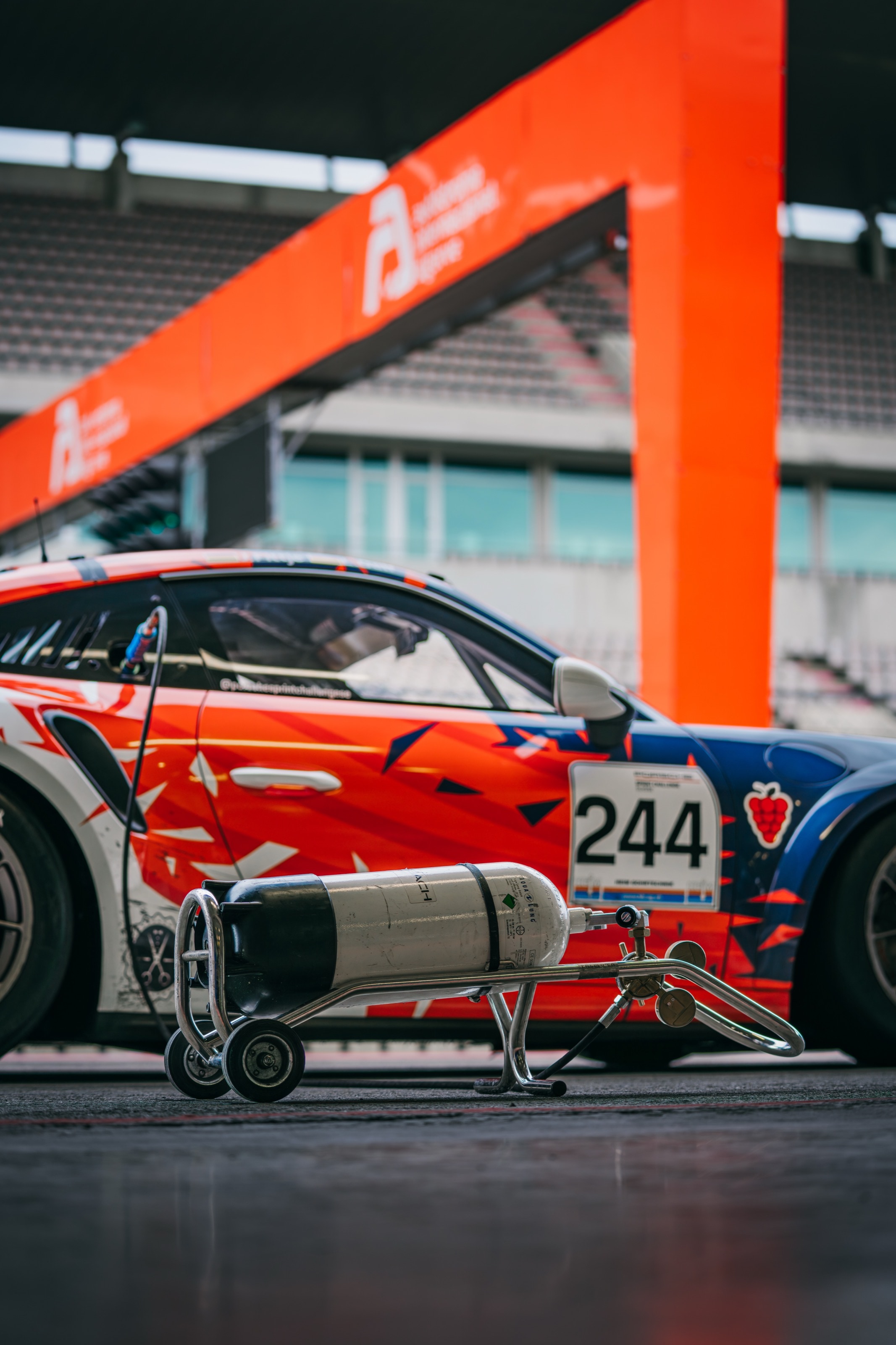 Der 911 GT3 Cup mit Startnummer 244 vor dem orangefarbenen Bogen in Portimão, daneben die Druckluftflasche
