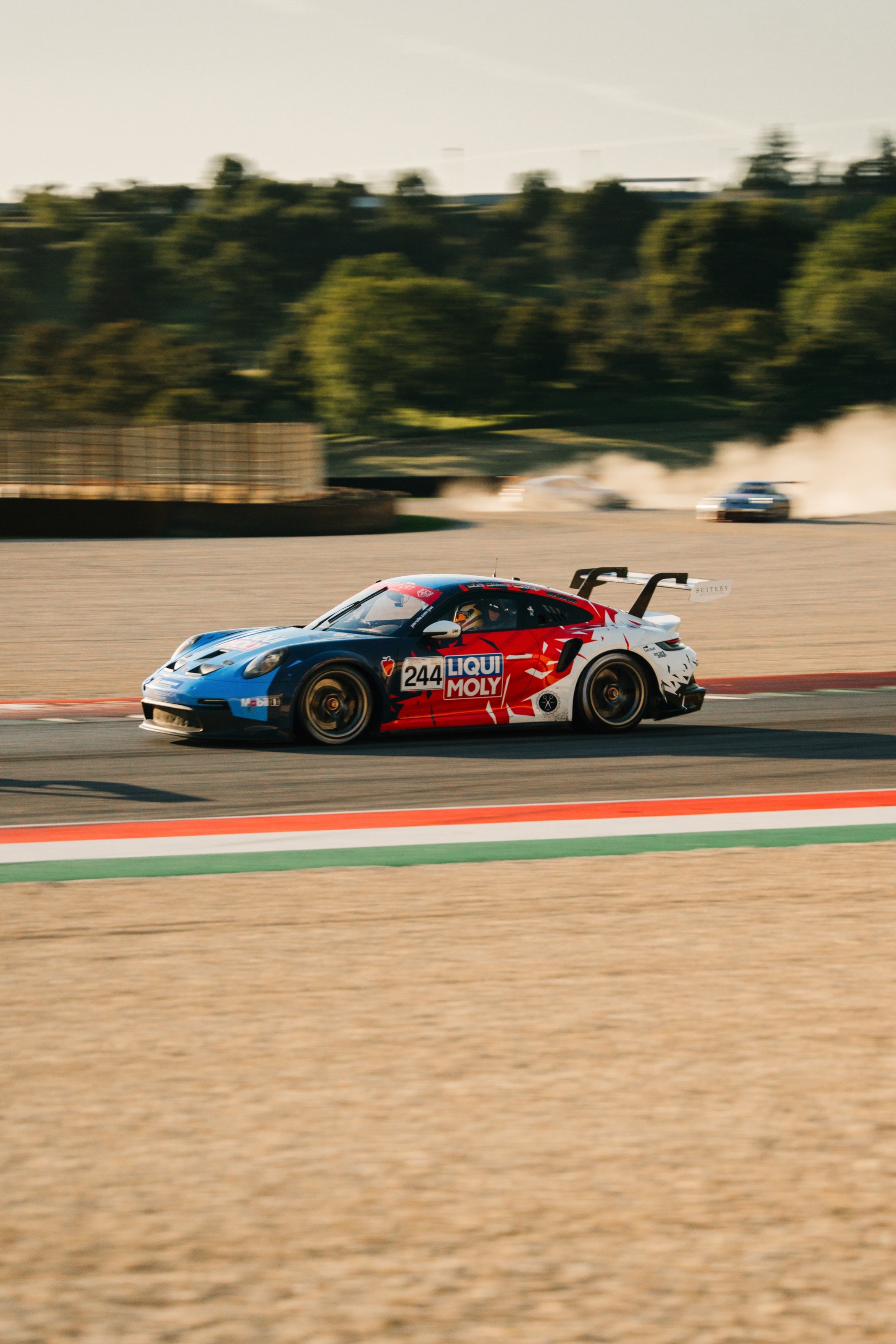 Der 911 GT3 Cup auf der Strecke, dahinter wirbelt ein Konkurrent eine Staubwolke auf