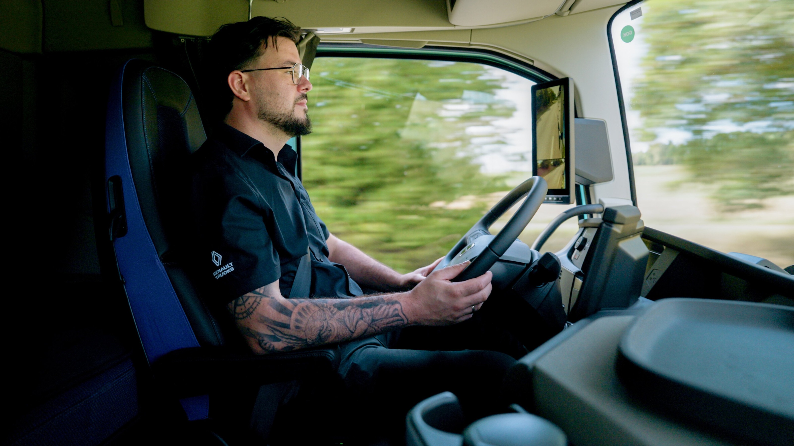Fahrer im Profil am Lenkrad des Volvo FH Aero Electric, hinter dem Seitenfenster zieht Grün vorbei